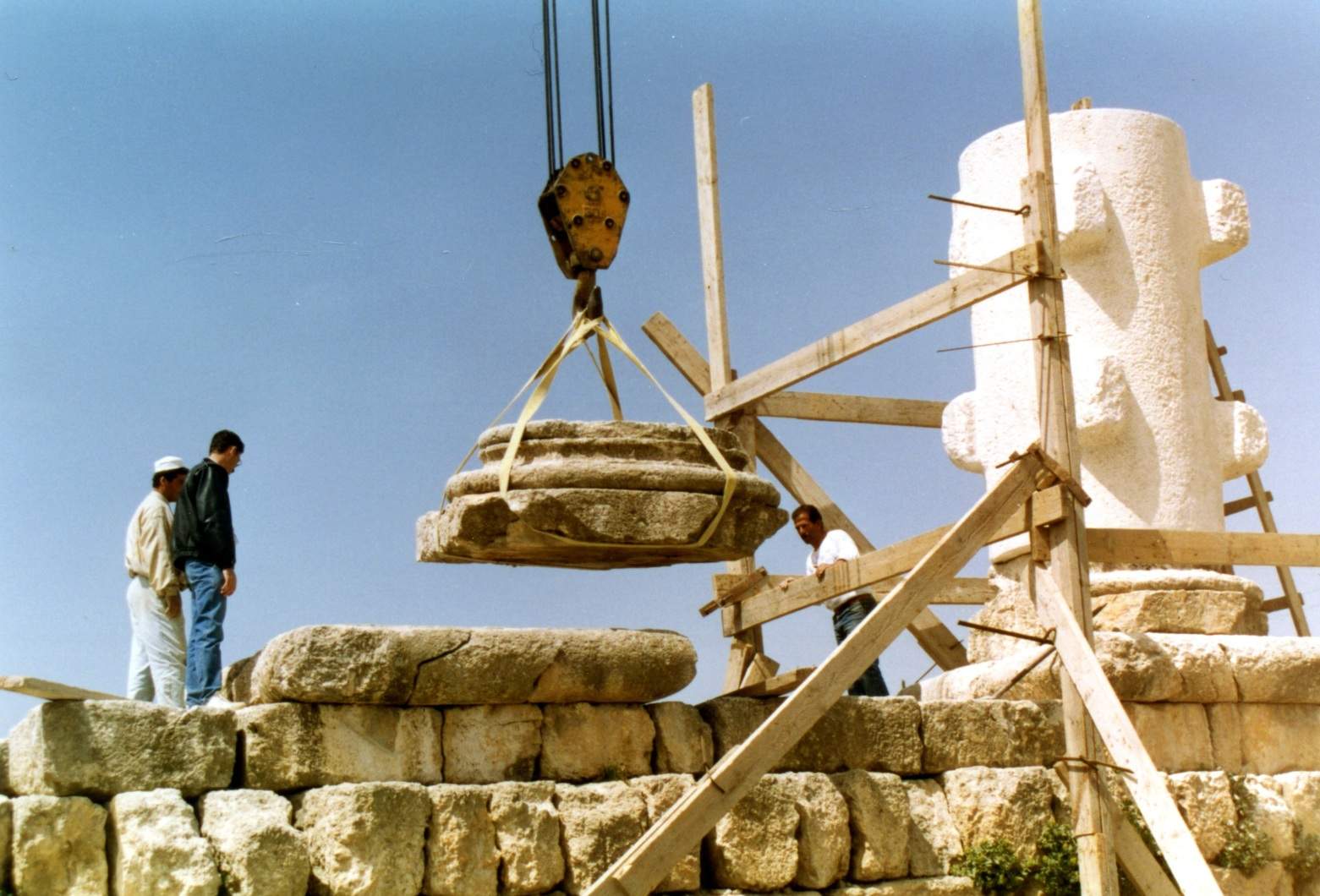 ACOR project members use a crane to raise one of the temple's monumental column bases into place. To the right is one of the four newly carved column drums that was needed to complete the reconstruction. Photo from ACOR Archive.