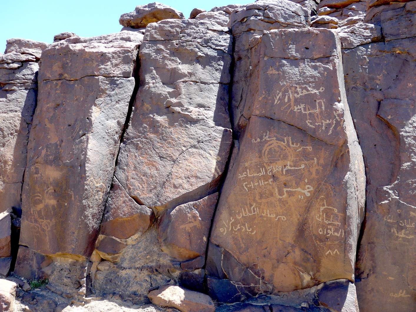 Cliff face containing rock art at Wadi Hassan. On the right column, notice the modern Arabic writing that covers the much earlier drawing of an ibex. Photo by C.D. Allen.