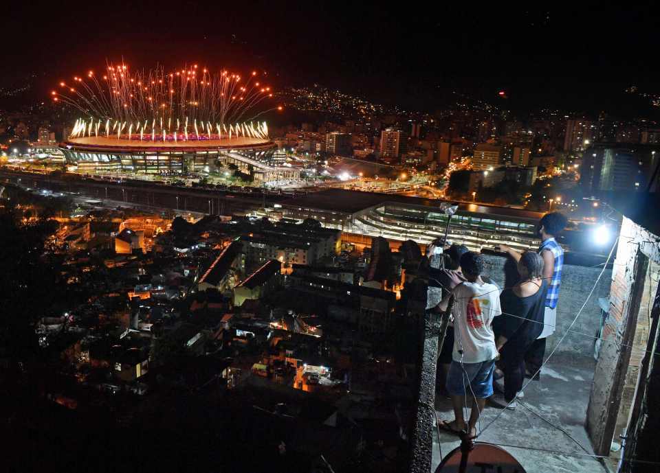 People watch fireworks exploding over the Maracana stadium, from a terrace in the favela Mangueira, during the opening ceremony of the Rio 2016 Olympic Games in Rio de Janeiro on August 5, 2016. / AFP PHOTO / Andrej ISAKOVICANDREJ ISAKOVIC/AFP/Getty Images